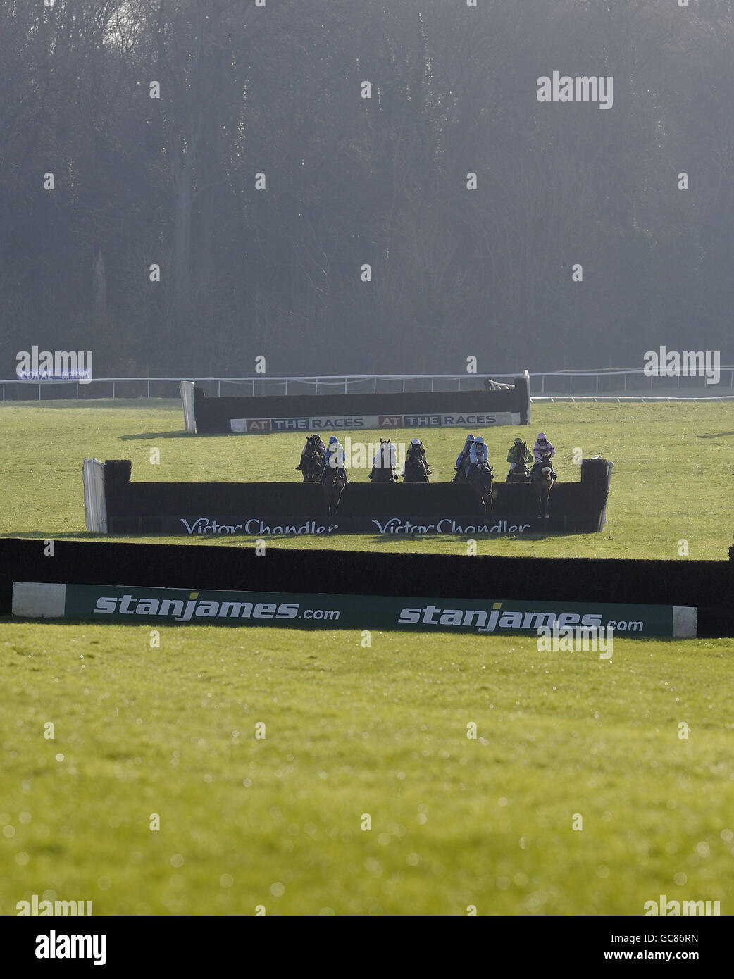 Runners and riders take a fence in the back straight in The coral.co.uk Hadicap Steeple Chase during the Coral Welsh National at Chepstow Racecourse, Gwent, Wales. Stock Photo