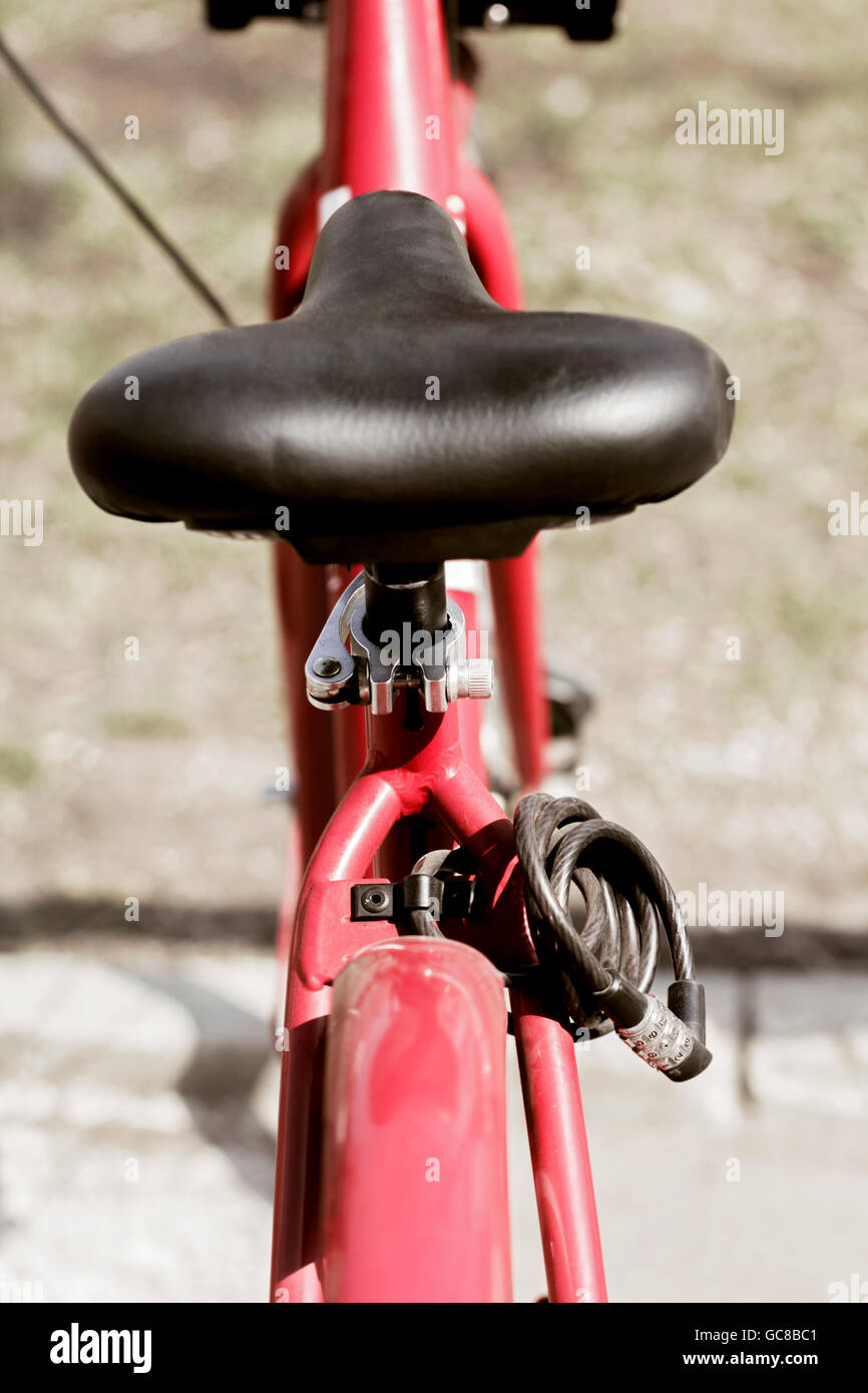 Black bicycle saddle on red at sunny day Stock Photo