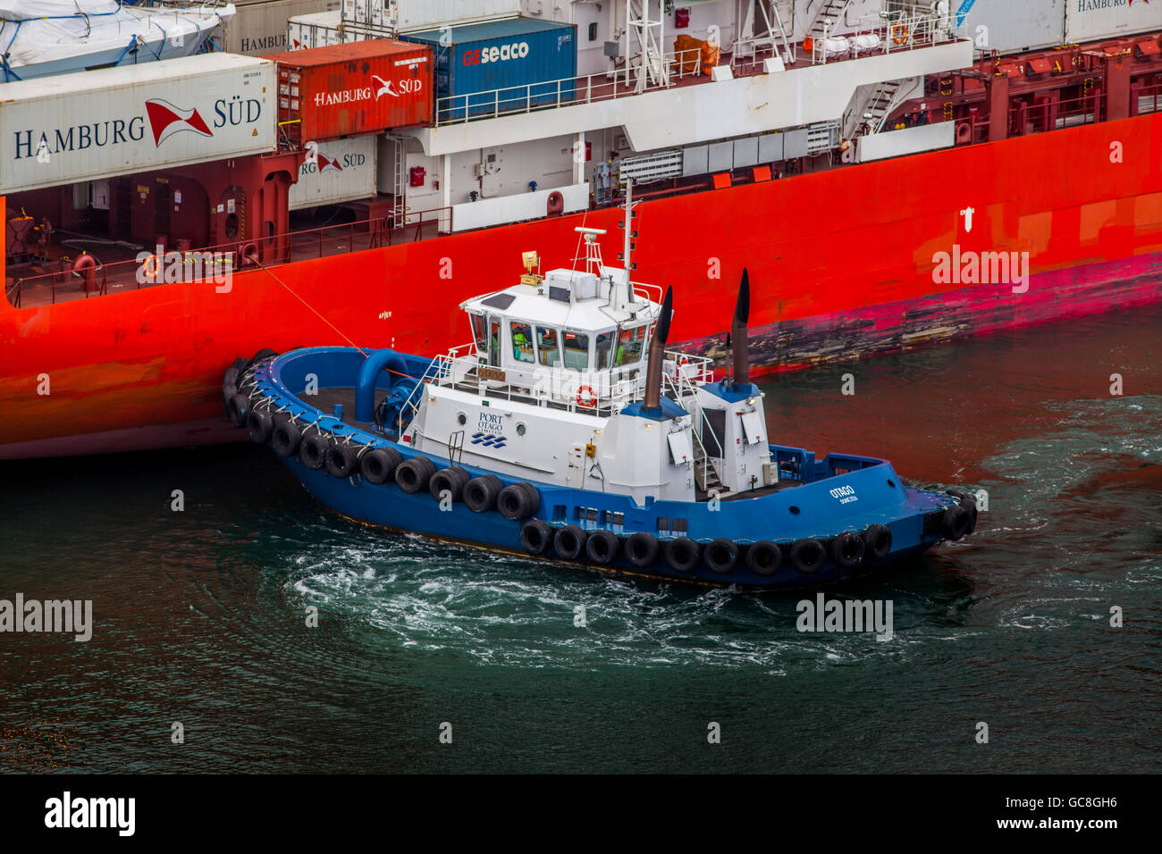 Tug boat pushing container ship in Port Chalmers,Dunedin,Otago,South