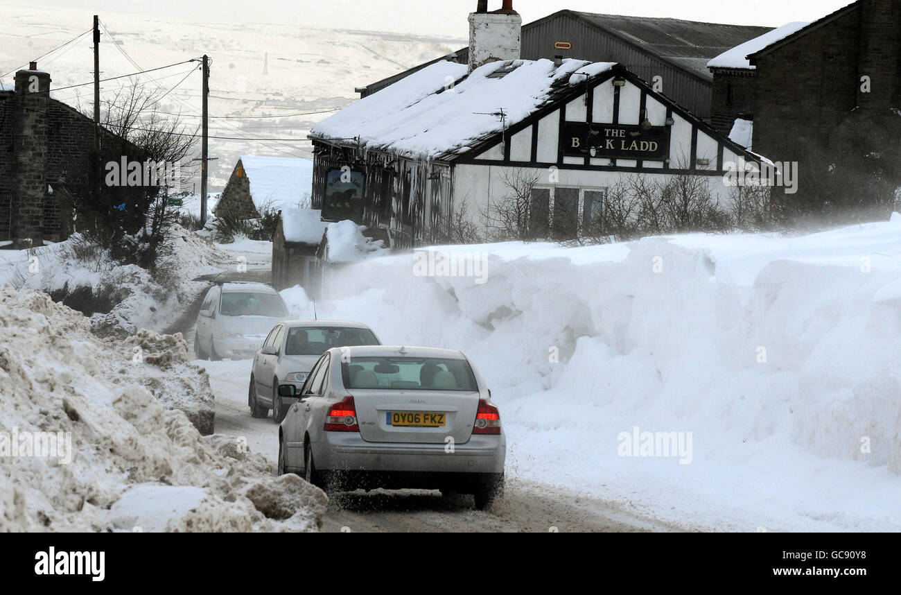 Cars pass a wall of snow after a team of diggers cleared snow drifts ...