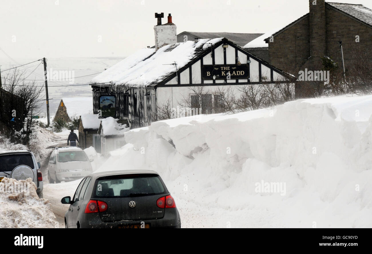Cars pass a wall of snow after a team of diggers cleared snow drifts ...