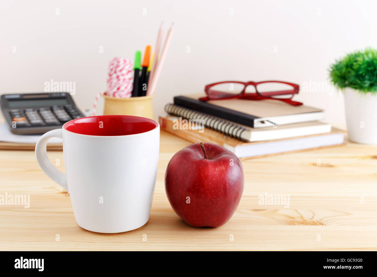 White coffee mug mockup with red apple on wooden table Stock Photo