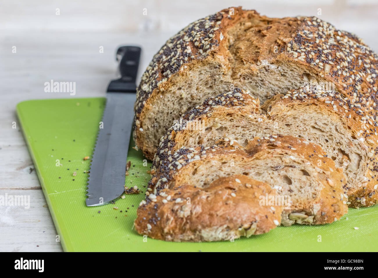 Loaf of bread and knife on a green cutting board Stock Photo