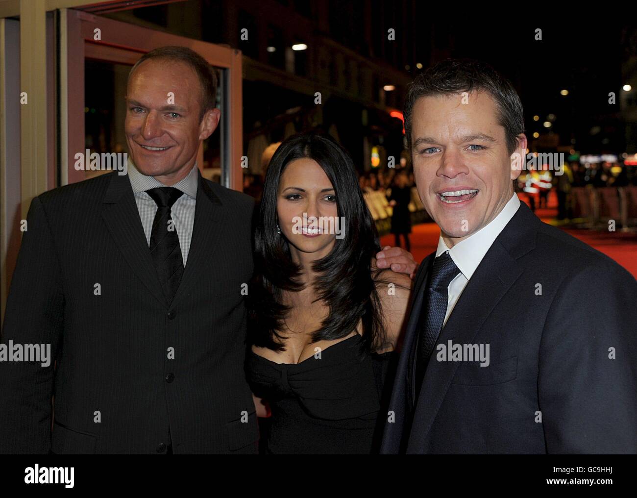 Matt Damon (right), his wife Luciana Barroso (centre) and Francois Pienaar arriving for the UK premiere of Invictus at the Odeon Leicester Square, London. Stock Photo