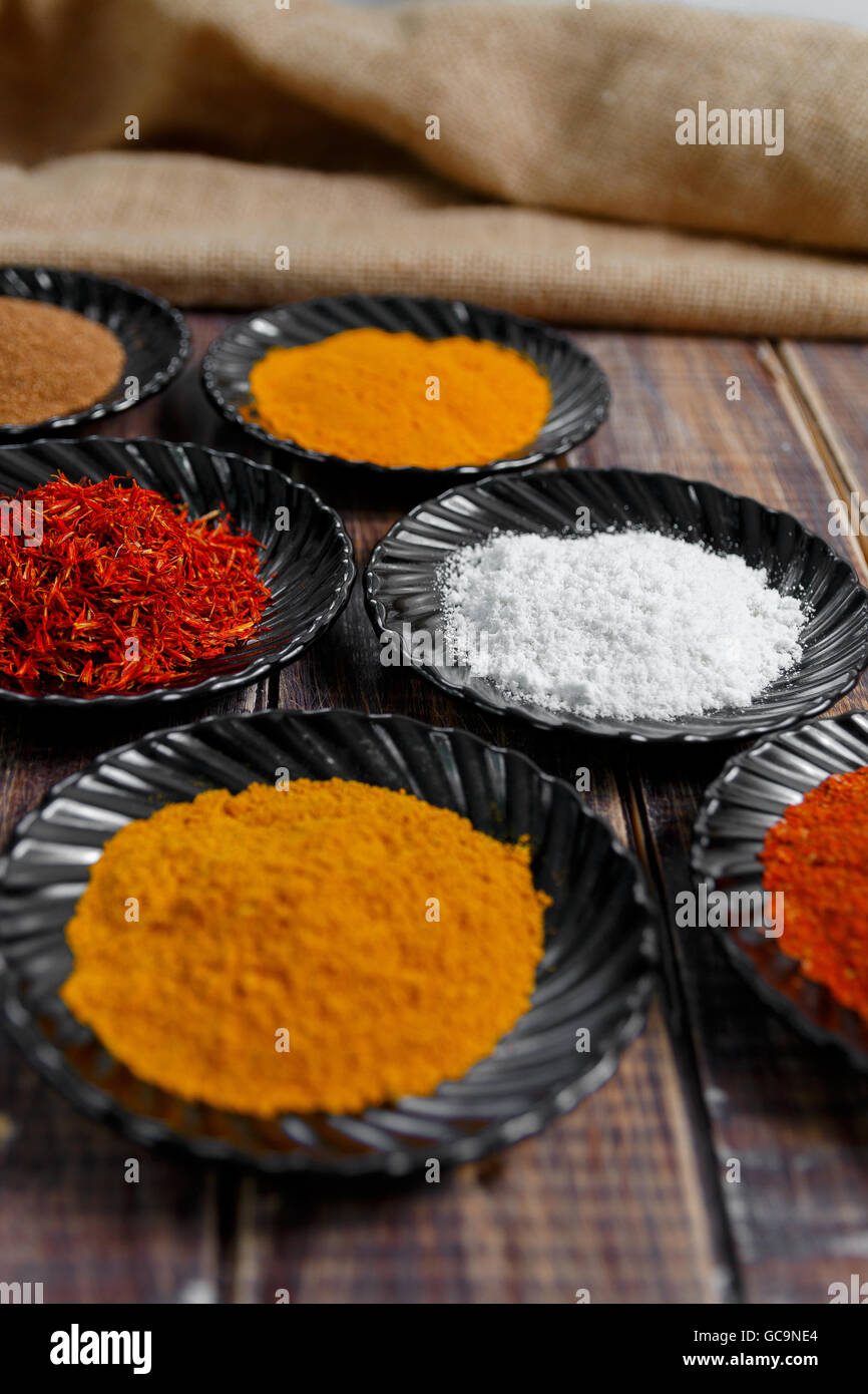 Spices in black ceramic plates on wooden background. Various spices ...