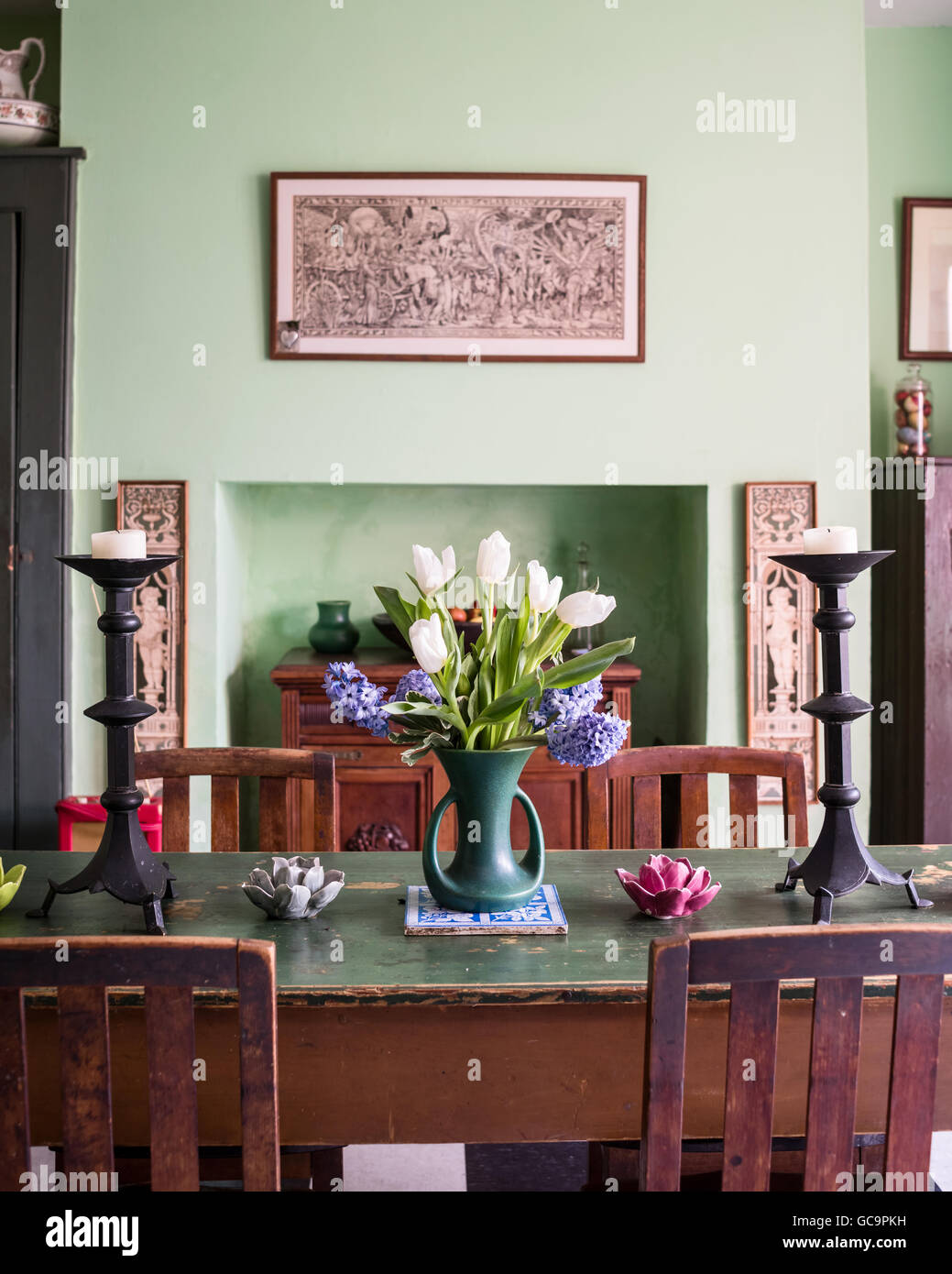 Tulips and candlestick on dining table with William Morris style oak chairs, Nottinghill, London, UK Stock Photo