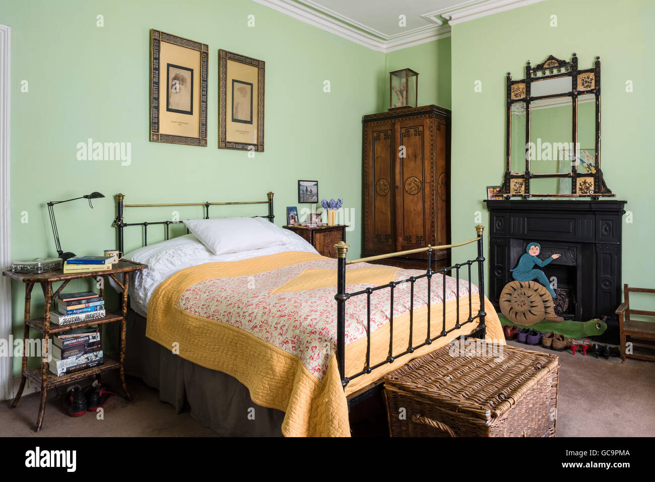 Original prints of Sarah Bernhardt by Nadar hang above French iron bed with Arts and Crafts ebonised and gilt mirror Stock Photo