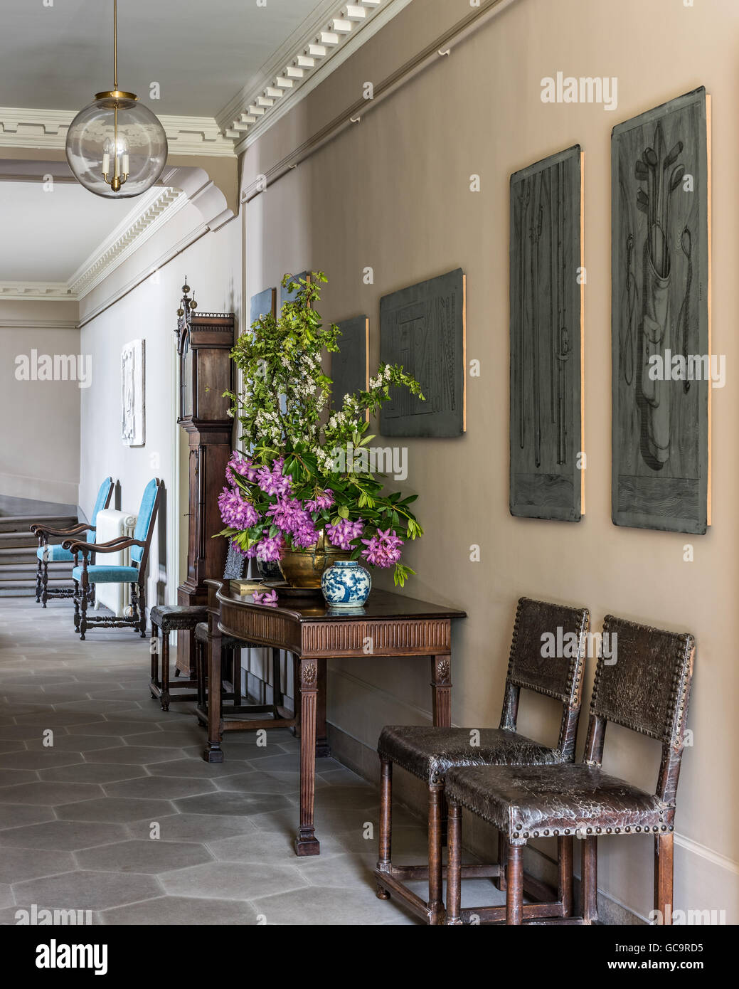 Pale grey octagonal stone floor in hall with old Fornasetti lead printing plates on the wall Stock Photo