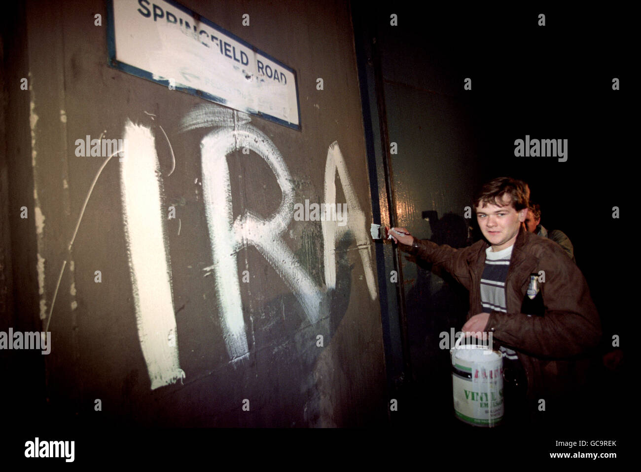 A SUPPORTER PAINTS IRA ON THE WALL OF SPRINGFIELD ROAD POLICE STATION