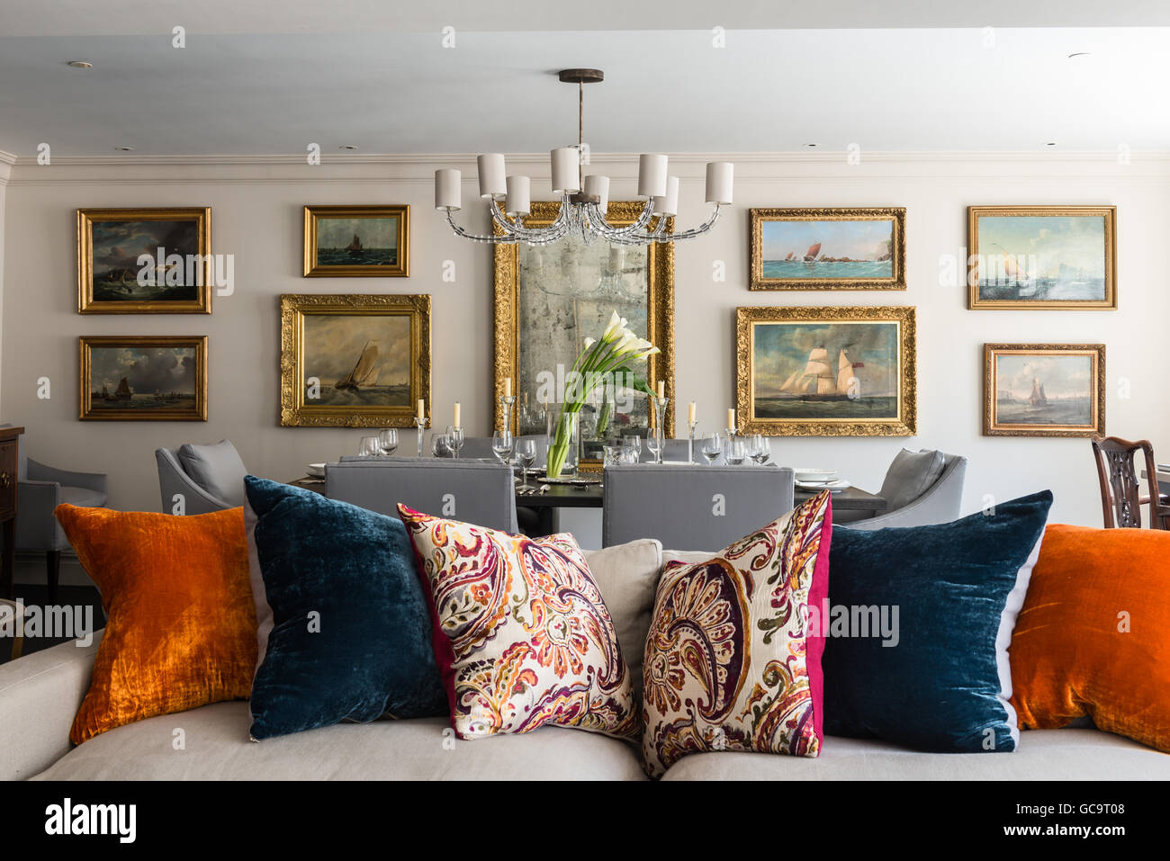 Assorted velvet cushions from Inky Velvet on sofa in sitting room with gilt framed maritime  paintings Stock Photo