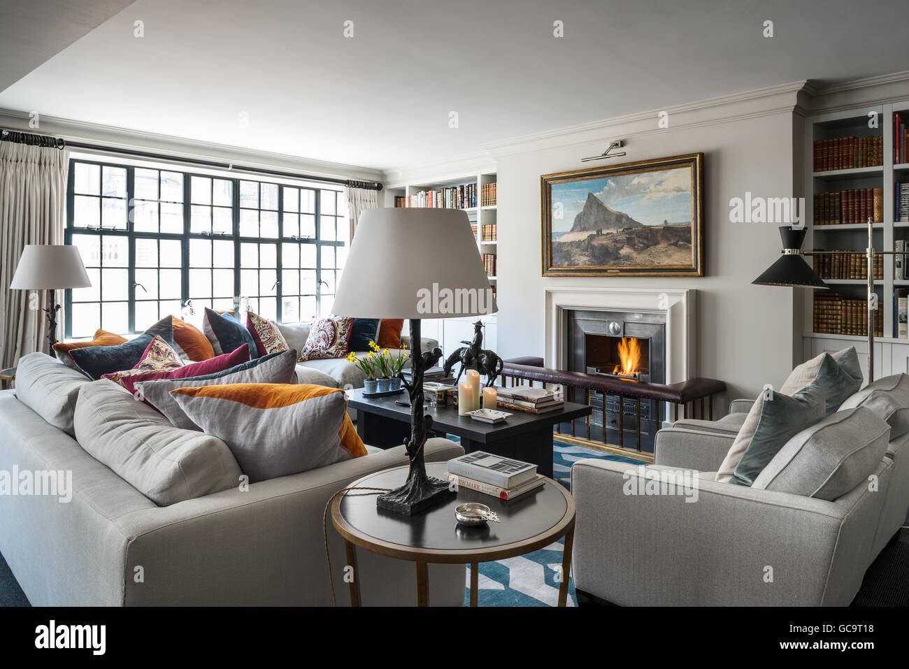 Pair of linen upholstered sofas and armchairs designed by Stephanie Everard in living room with windows Stock Photo