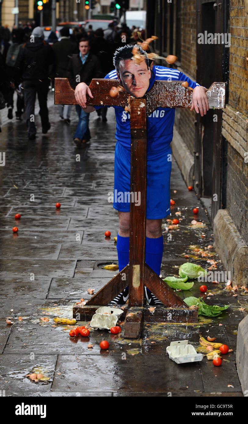 A man in a John Terry mask is put in the stocks and pelted with eggs and fruit by the public outside the London Dungeon. Stock Photo