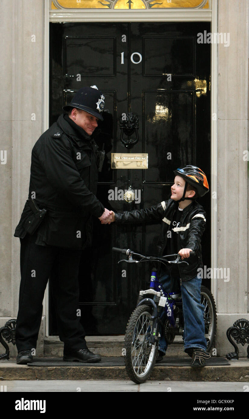 Charlie Simpson, 7, from Fulham, west London, who has raised over 160,000 for Unicef's Haiti Earthquake Children's Appeal with a sponsored cycle ride, shakes hands with a policeman outside 10 Downing Street, Westminster, London. Stock Photo