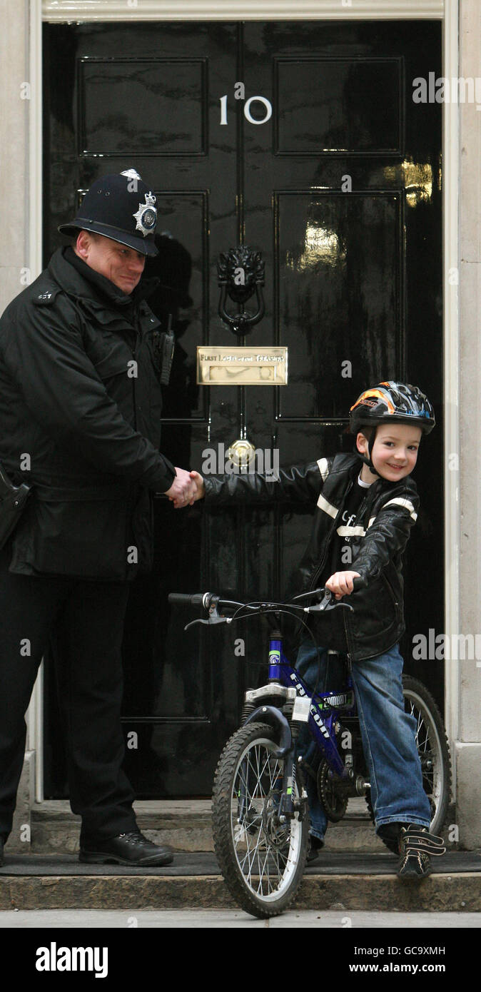 Charlie Simpson, 7, from Fulham, west London, who has raised over 160,000 for Unicef's Haiti Earthquake Children's Appeal with a sponsored cycle ride, shakes hands with a policeman outside 10 Downing Street, Westminster, London. Stock Photo