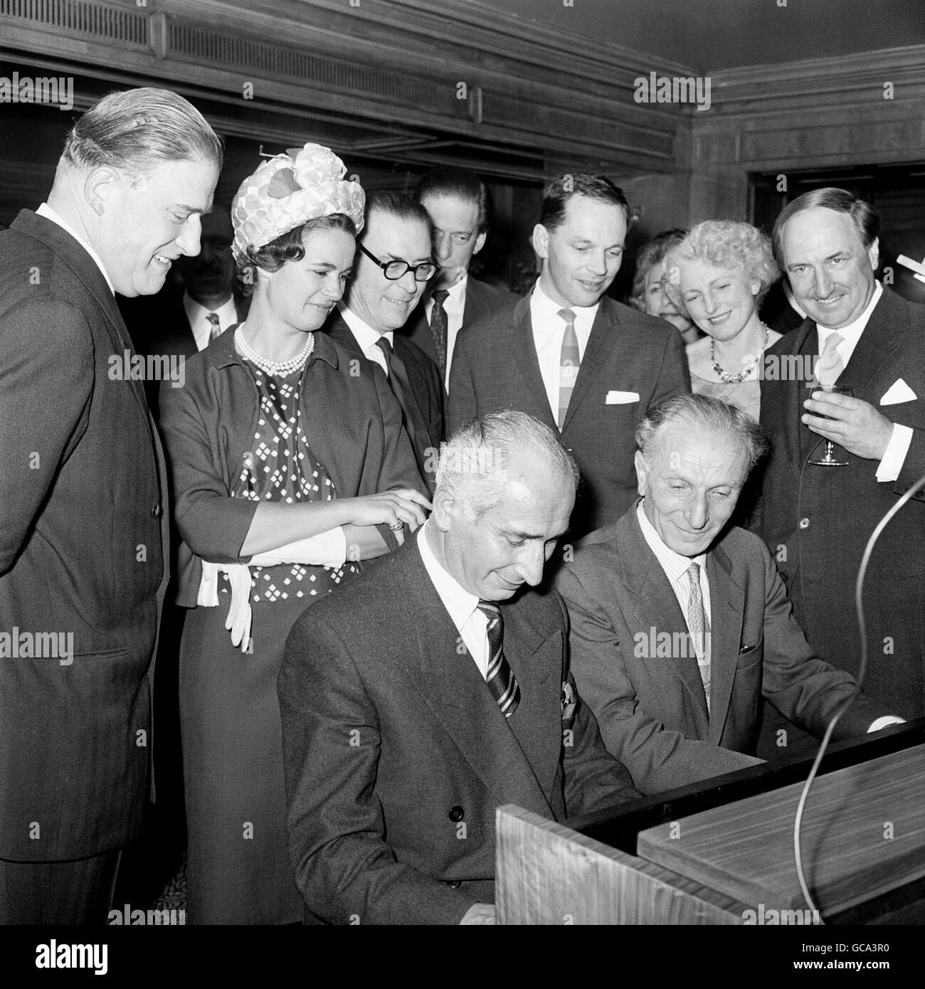 The Countess of Harewood, her borther-in-law The Hon. Gerald Lascelles (l), her husband the Earl of Harewood, (background) and Johnny Dankworth, the band leader, are obviously enjoying the music provided by Walter Landauer (of the Rawicz and Landauer piano team) (l) and Sidney Harrison. Stock Photo