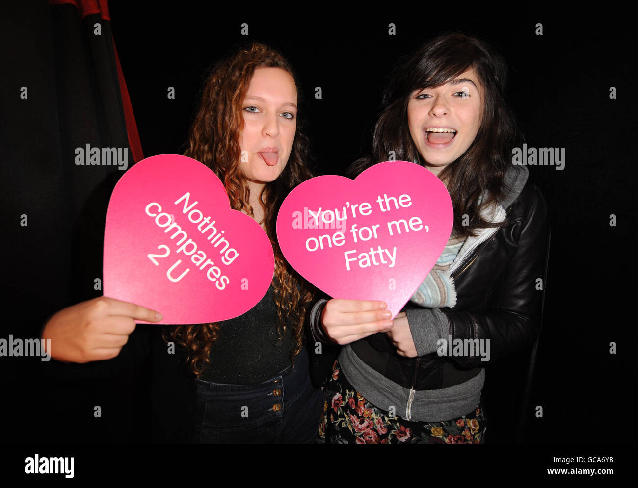 Danni Goodwin (left) aged 15 and friend Hannah Clarke aged 15 from London pose for a photo inside the Valentines Love Shack photo booth at HMV Oxford Street in central London. PRESS ASSOCIATION Photo. Picture date: Saturday February 13, 2010. HMV customers were invited to take free photos of themselves and with their partners holding a romantic message of love on a heart shaped board. Each message takes its theme from a famous love song. Photo credit should read: Zak Hussein/PA Wire Stock Photo