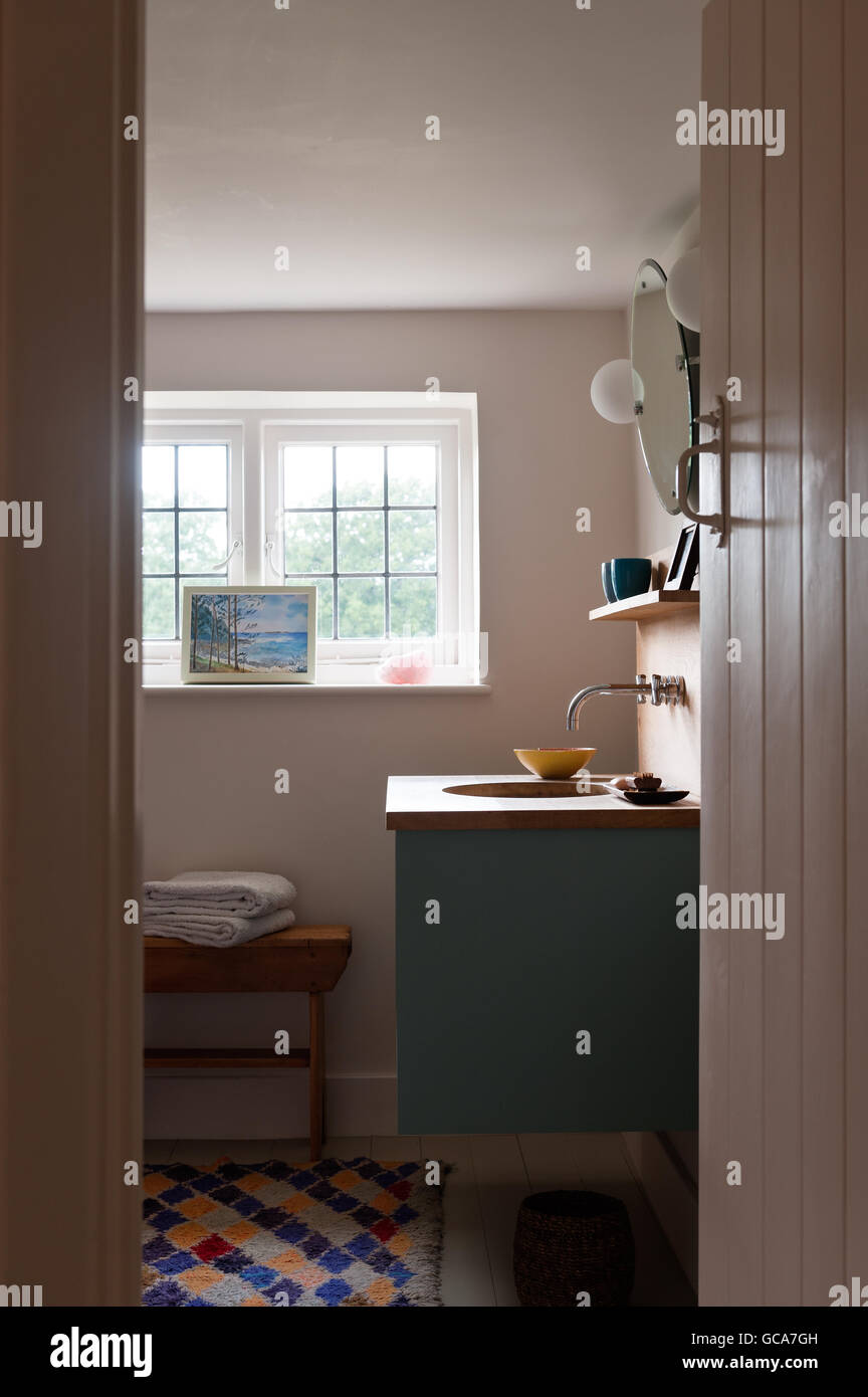 View into bathroom with oak topped vanity unit and patterned rug Stock ...