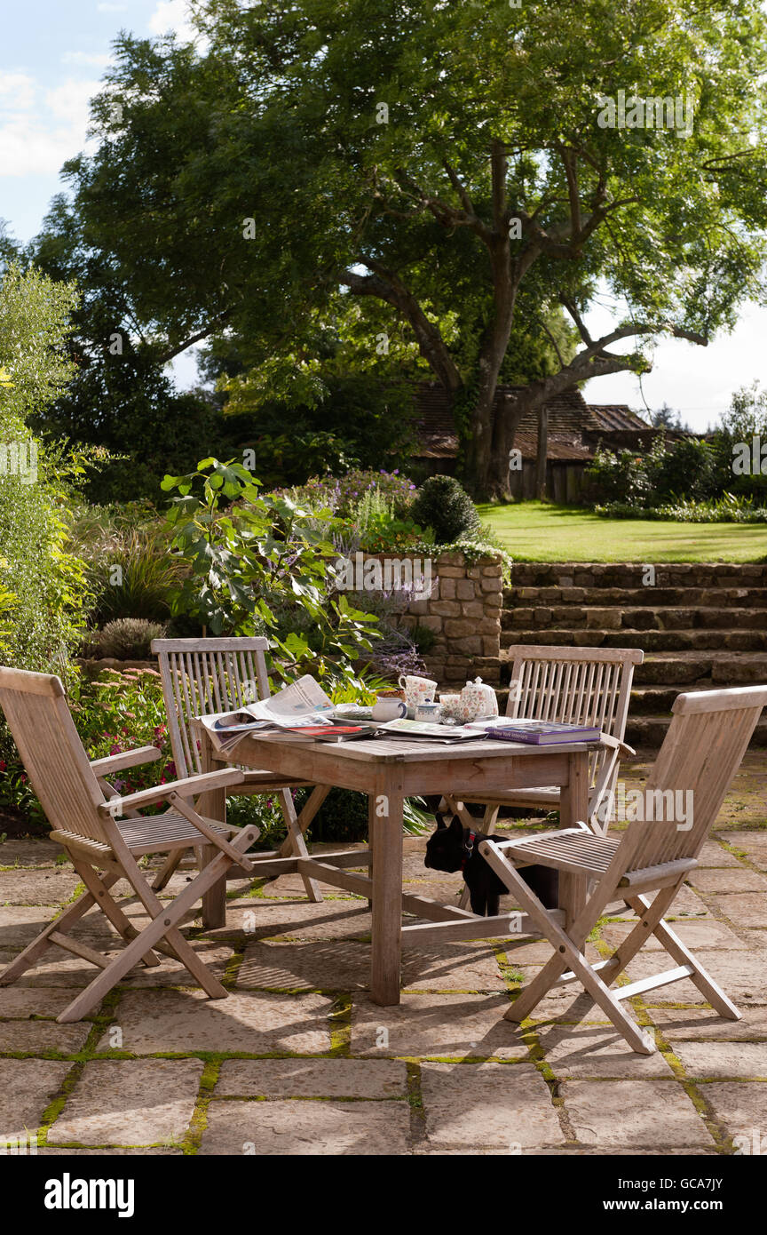 Garden furniture made to order from Andrew Crace in paved garden area with raised lawn. Stock Photo