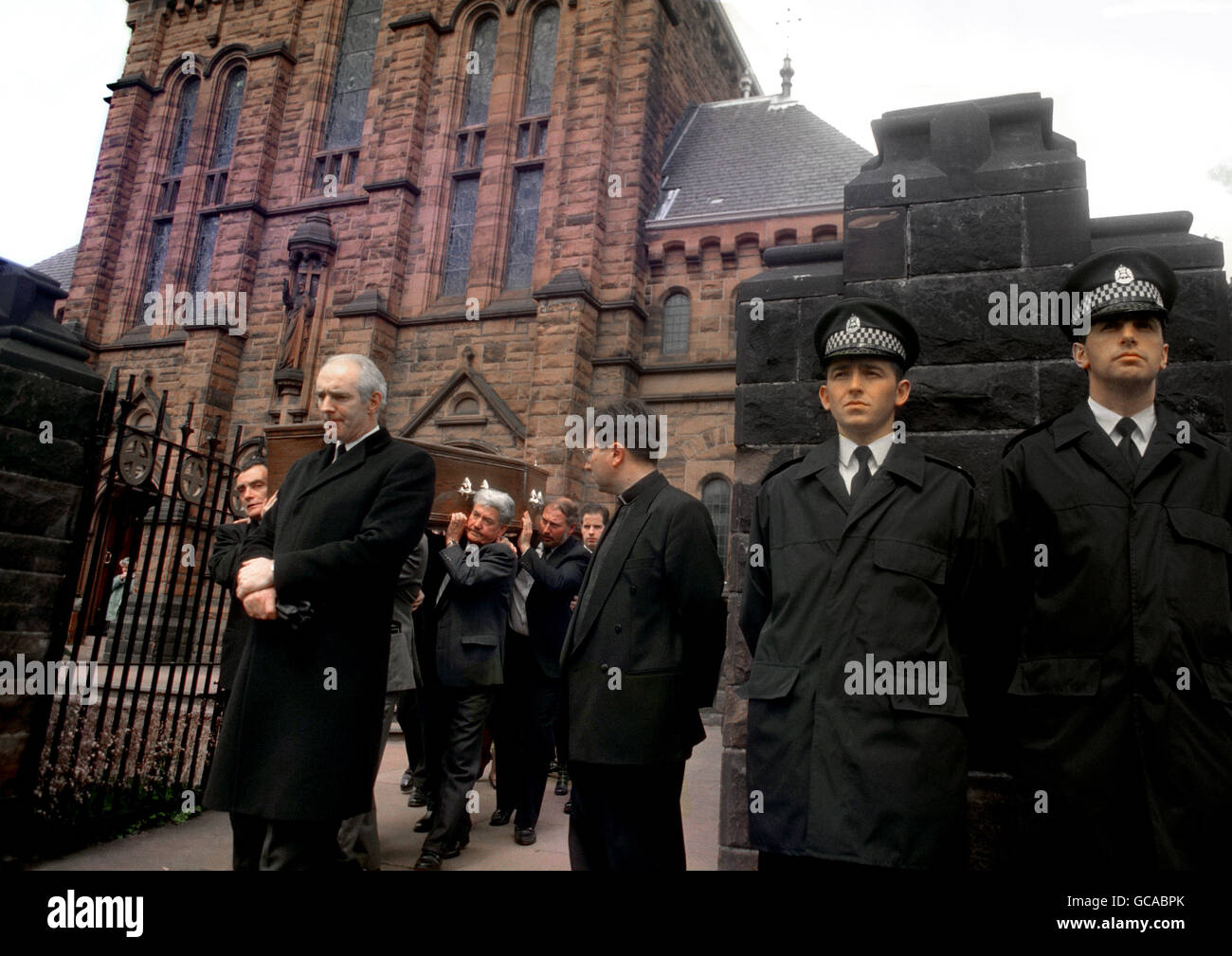 TWO POLICEMAN STAND IN SILENT TRIBUTE AS THE COFFIN OF ACTOR MARK MCMANUS, TV'S TOUGH TALKING DETECTIVE, TAGGART, IS CARRIED FROM THE HOLY CROSS ROMAN CATHOLIC CHURCH IN GLASGOW'S CROSSHILL. Stock Photo