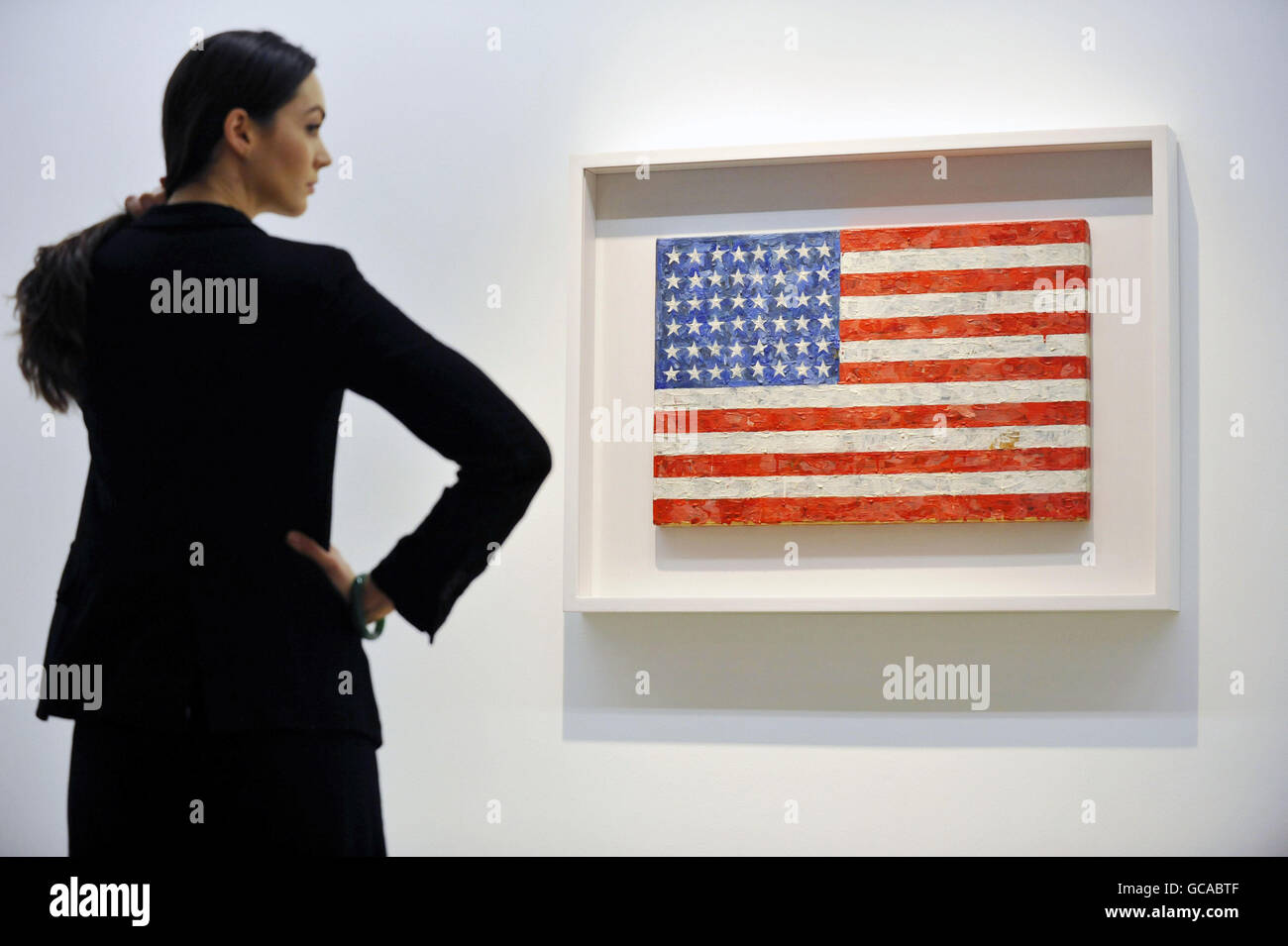 A Christie's employee poses with Jasper Johns' Flag, 1960-66, which is part of the collection of Michael Crichton on display at Christie's in London ahead of its auction on May 11. Stock Photo