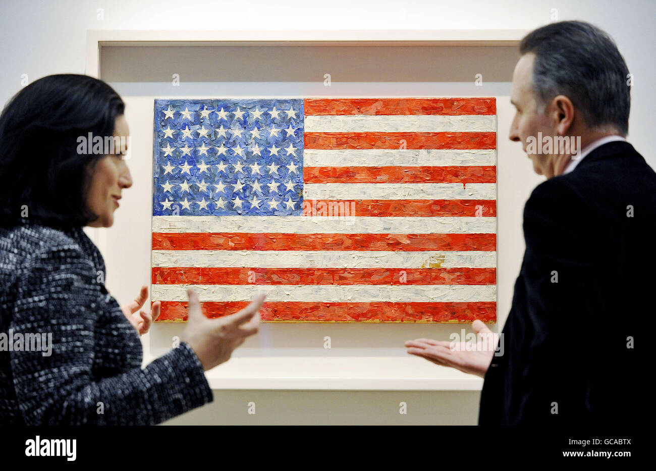 Visitors discuss Jasper Johns' Flag, 1960-66, which is part of the collection of Michael Crichton, on display at Christie's in London ahead of its auction on May 11. Stock Photo