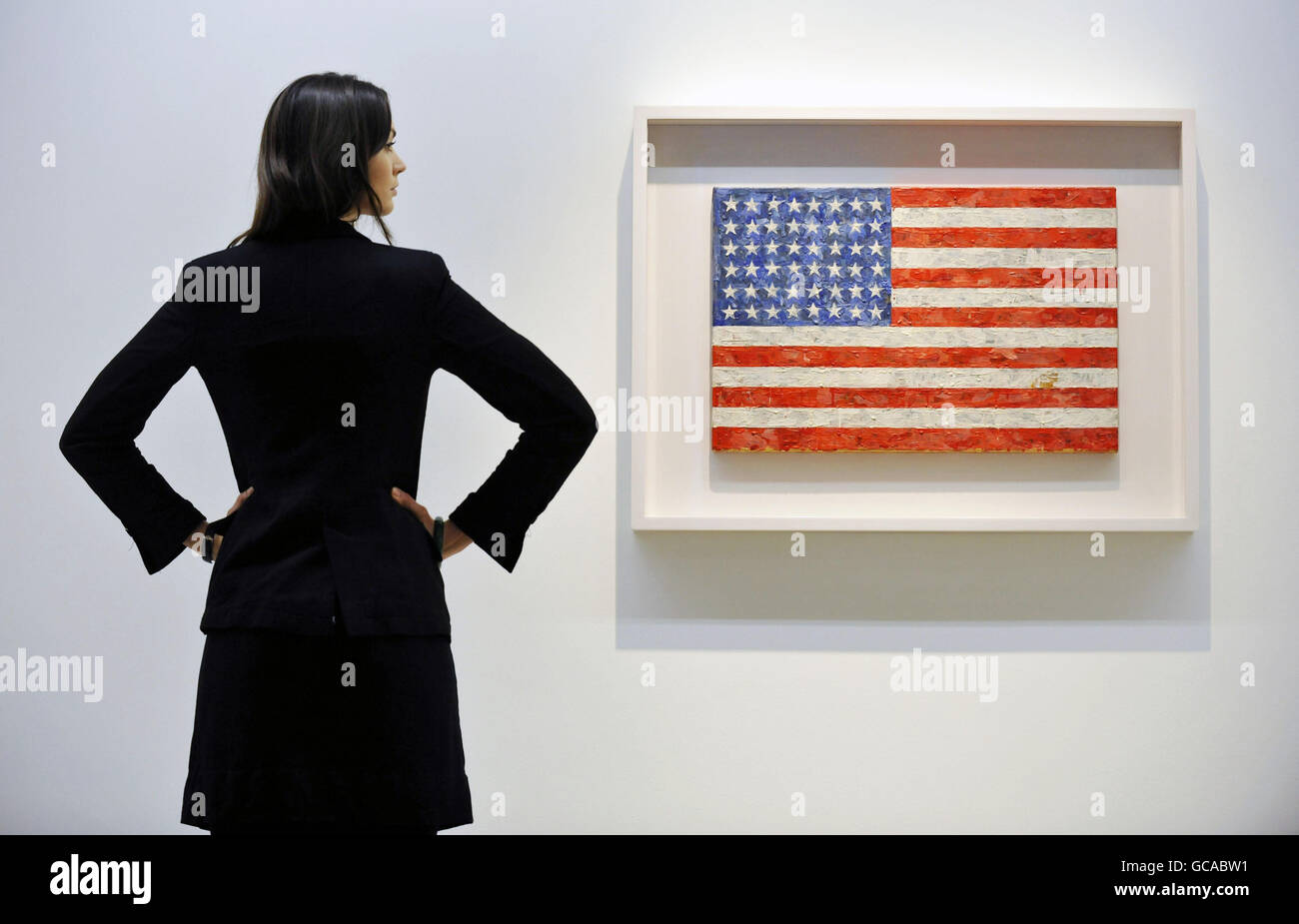 A Christie's employee poses with Jasper Johns' Flag, 1960-66, which is part of the collection of Michael Crichton on display at Christie's in London ahead of its auction on May 11. Stock Photo