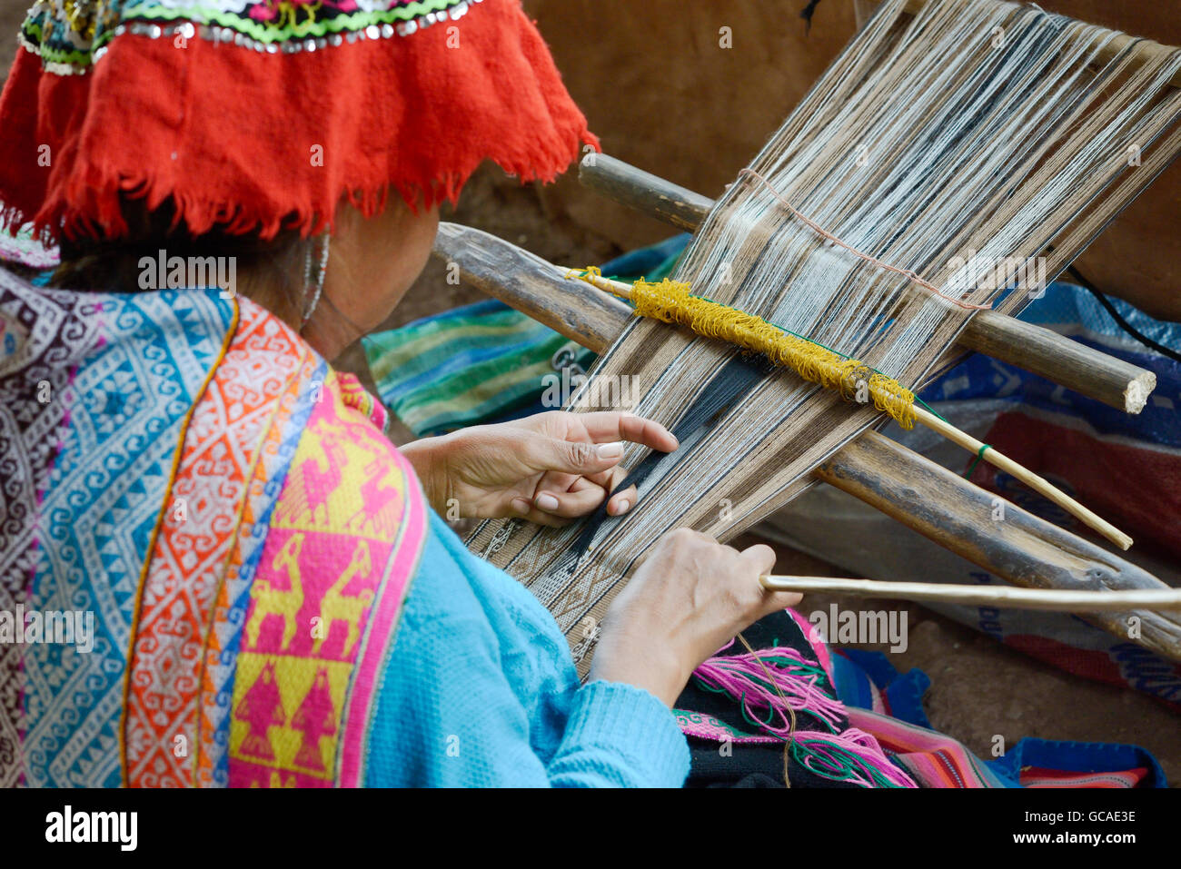 Peruvian woman in traditional clothing weaving cloth on a hand loom in the Andes Mountains, Peru Stock Photo