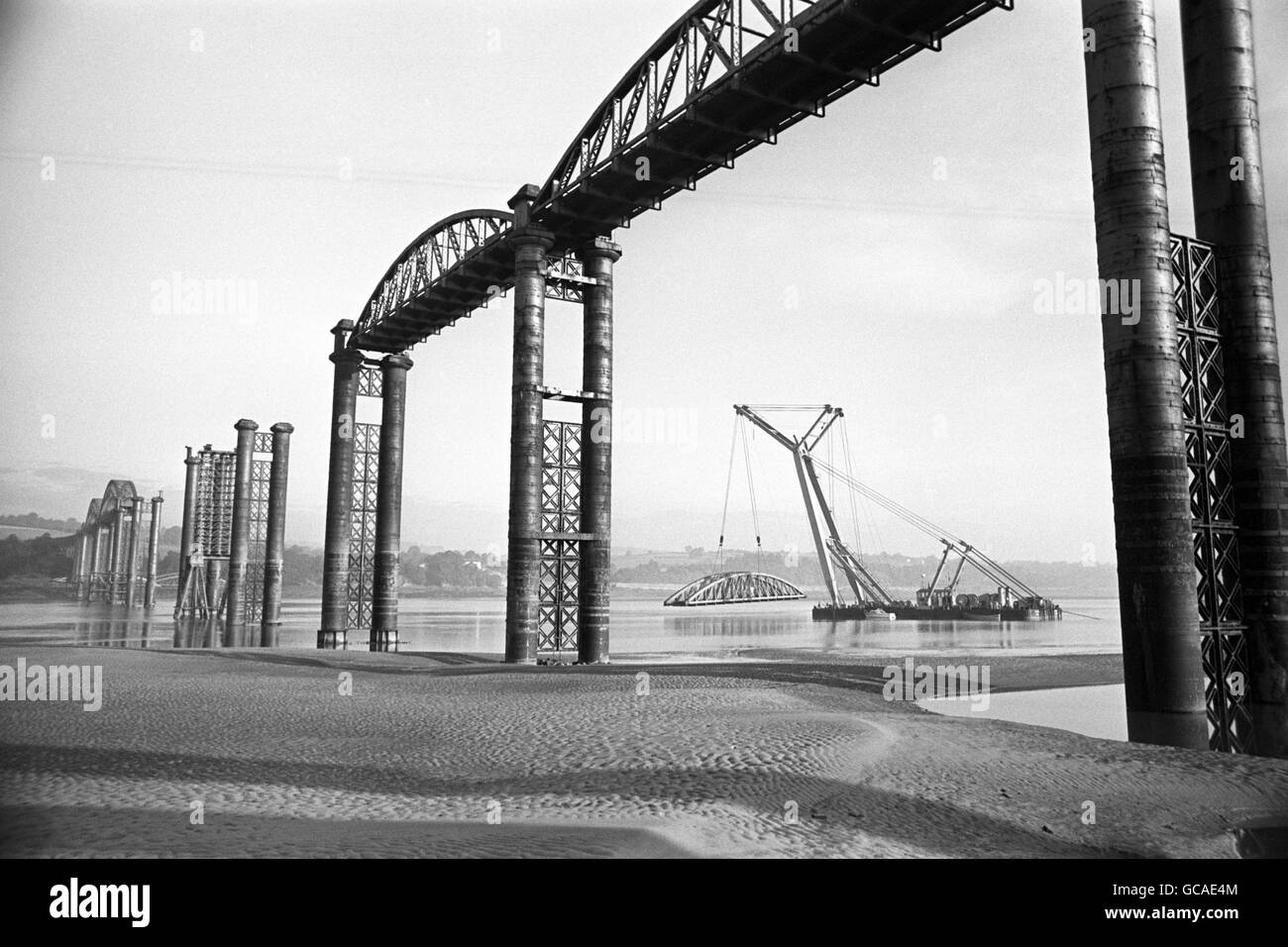 A bridge that was considered a marvel of it's age, gradually disappearing before your eyes. A German crane, capable of lifting 500 tins, is seen removing one of the spans of the old Severn Railway Bridge, which was badly damaged in a major accident seven years ago, during it's final demolition. Stock Photo