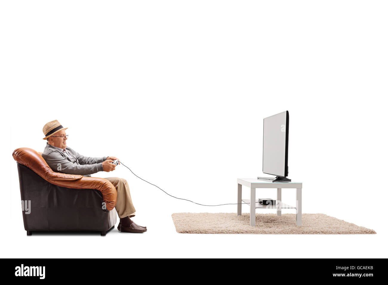 Studio shot of a joyful senior playing video games seated on an armchair isolated on white background Stock Photo