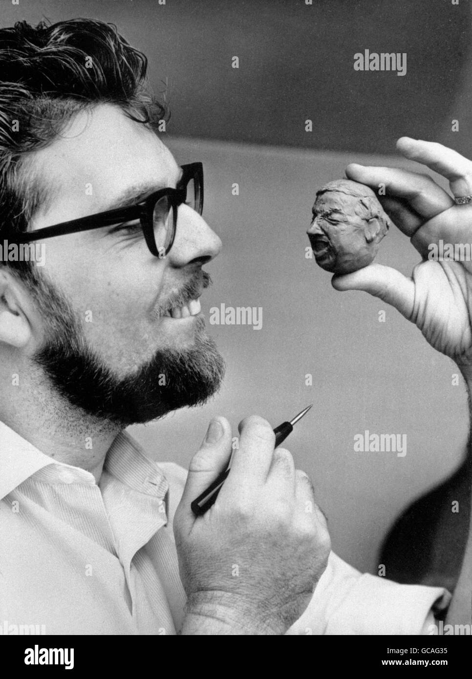 No, he's not turned headshrinker, just plasticine sculptor. And who is he? - Pop singer Rolf Harris, who fills in time between acts at the Royal Aquarium Theatre, Great Yarmouth, by sculpting heads. This one looks surprisingly like the actor Miles Malleson. Stock Photo