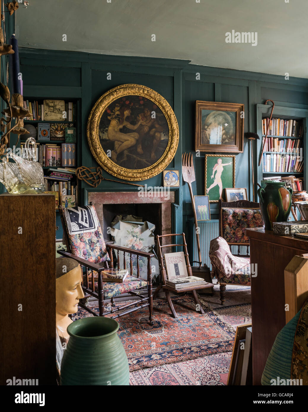 Quirky teal coloured wood panelled bedroom filled with diverse objects