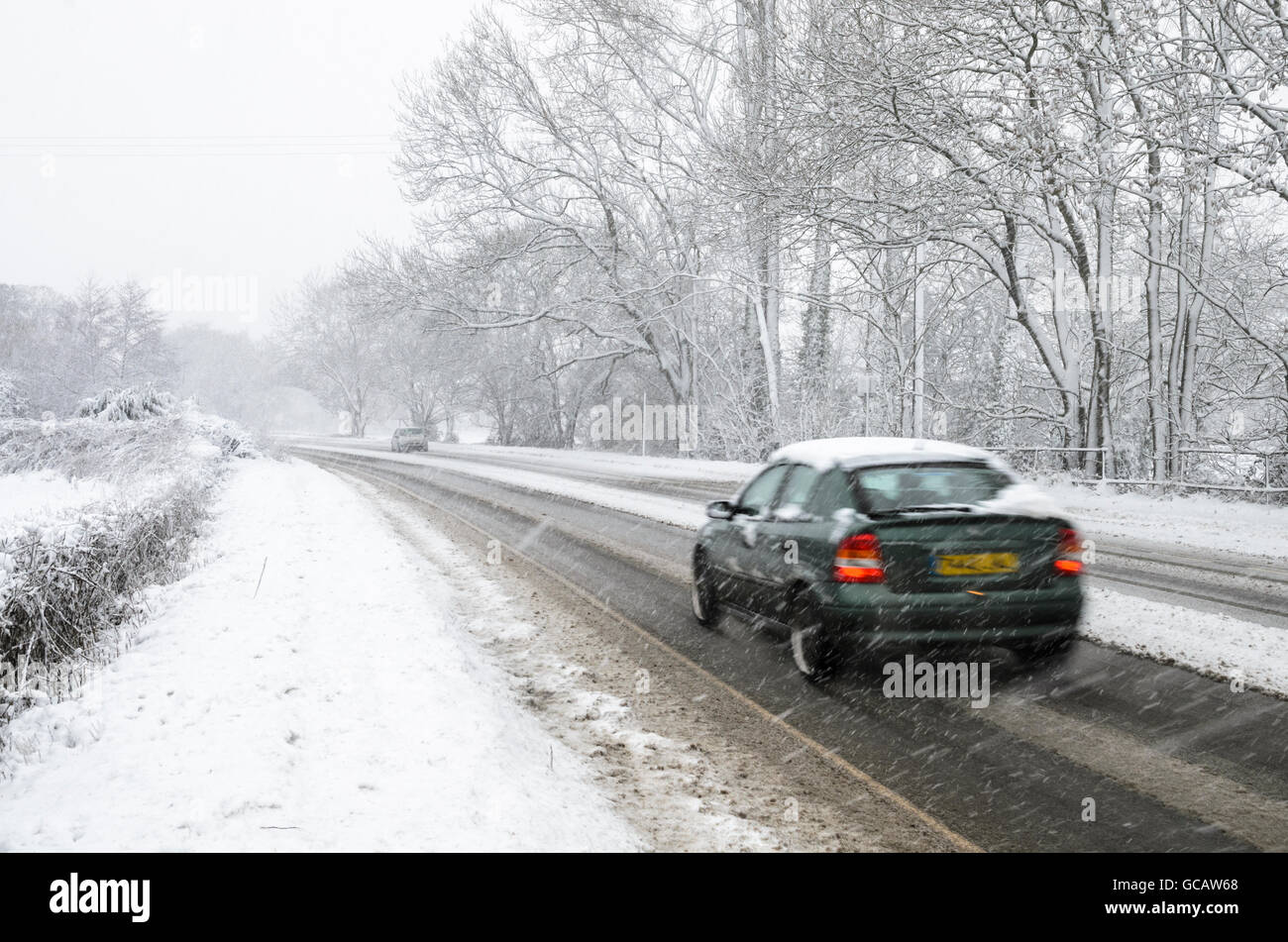 A motor car driven along a snow covered rural road in North Somerset, England. Stock Photo
