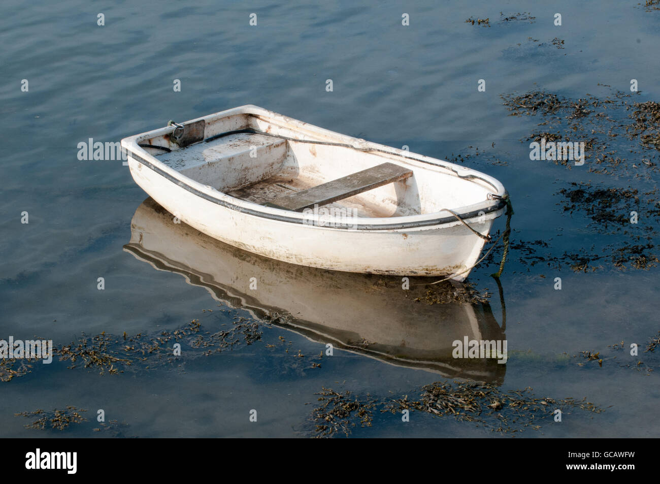 Small fishing boat at sunrise, moored in the water ready for sailing Stock Photo
