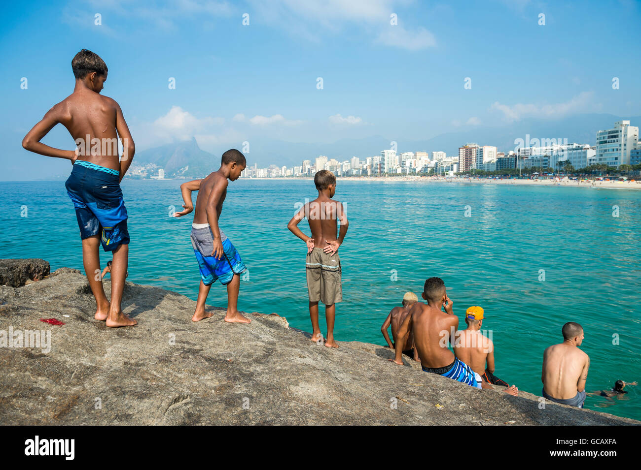 RIO DE JANEIRO - FEBRUARY 03, 2014: Group of young Brazilians gather to jump from the rocks at Arpoador near Ipanema Beach. Stock Photo