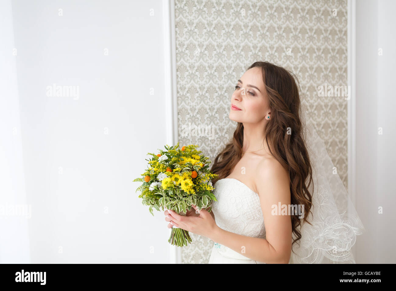 Happy bride holding a wedding bouquet in a studio Stock Photo