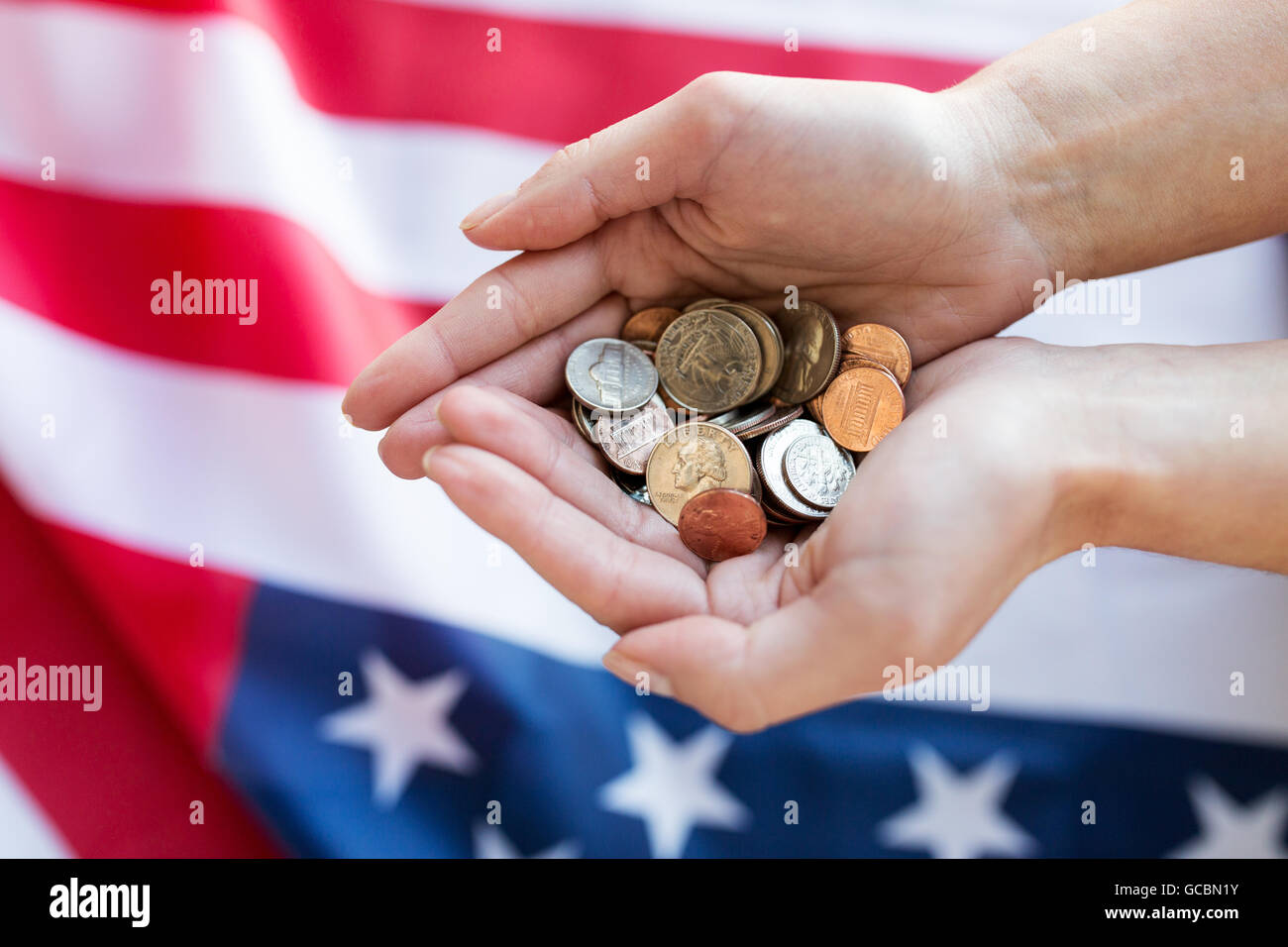 close up of hands with coins over american flag Stock Photo