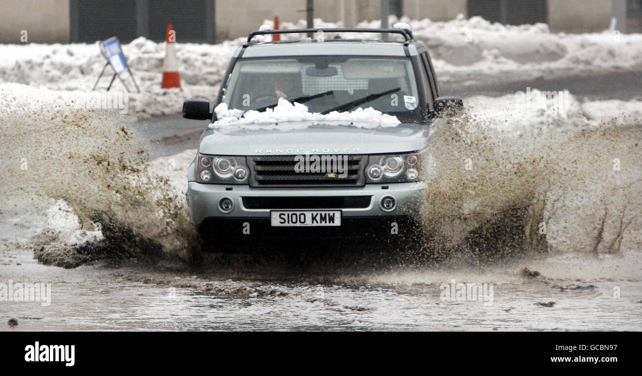 A car drives through water on a road in Newton Mearns after heavy snow falls across Scotland overnight. Stock Photo