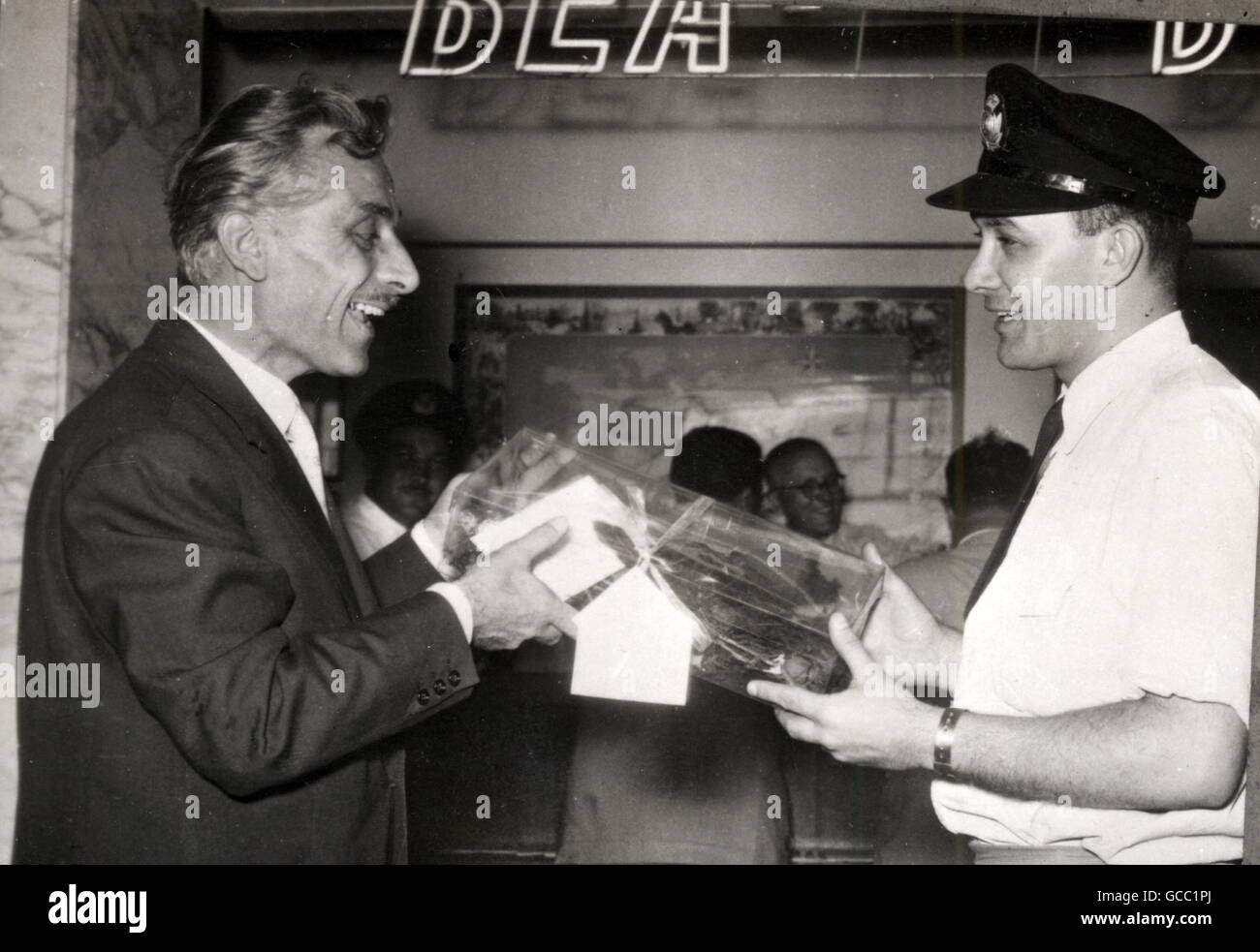 Renato Marmiroli (left), who wants to fight a duel with the Queen's critic, Lord Altrincham, is seen delivering a golden rose as a personal gift to the Queen at the British European Airways office at Rome's Ciampino International Airport. Signor Marmiroli , a former officer of the Italian artillery, sent the rose as a token of his unshakable devotion to the Queen. Stock Photo