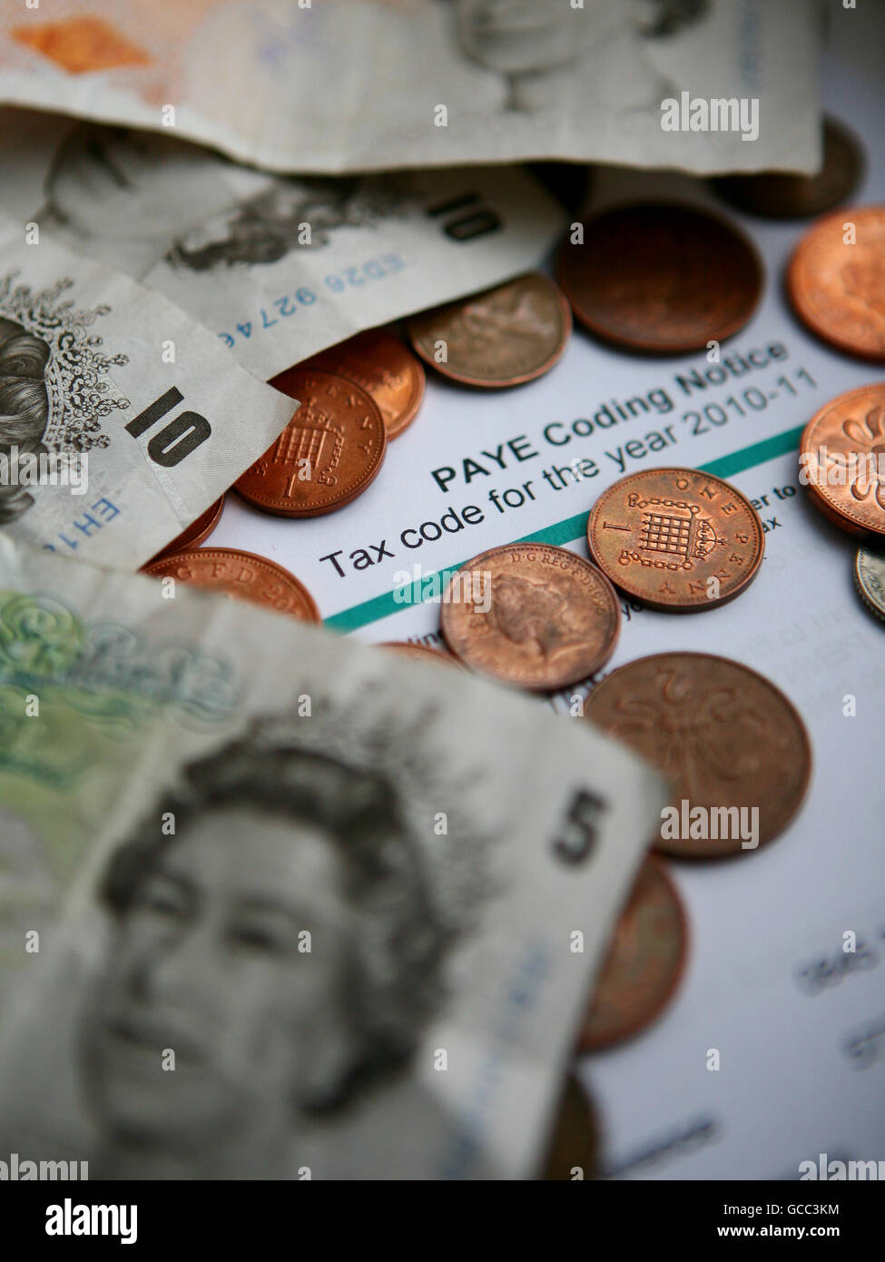 A PAYE Tax Code Notice surrounded by five and ten pound notes. Stock Photo