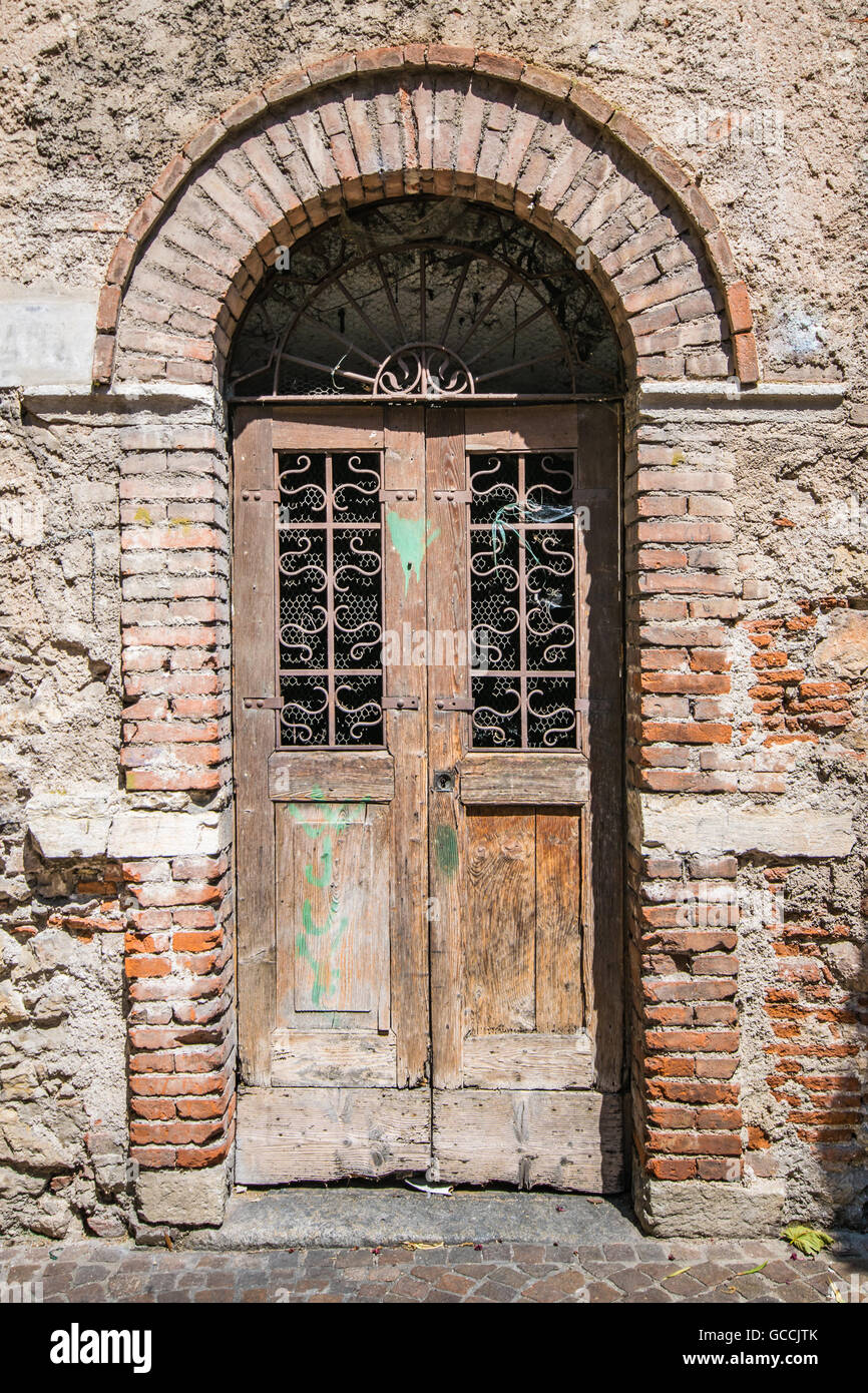 Old wooden door with upper railing and brick archway. Stock Photo