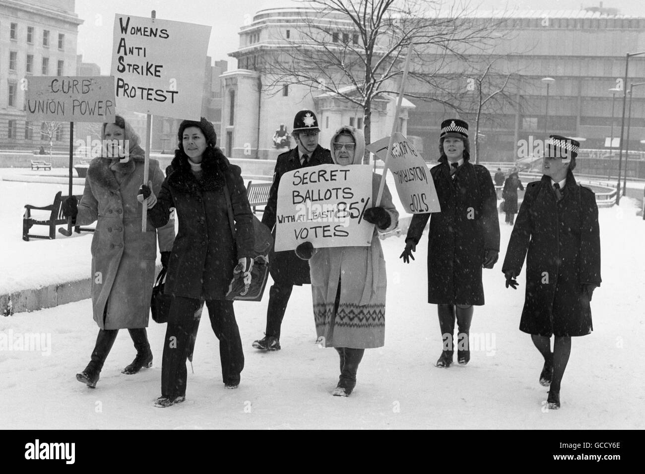 A police escort for these angry women in Birmingham as they march through the snow to deliver a housewives' anti-strike petition to the offices of the Transport and General Workers' Union. Stock Photo