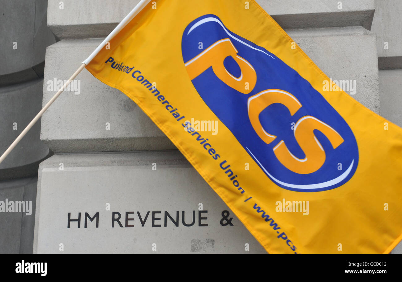 A banner from the Public and Commercial Services (PCS) union is held by a picket outside the headquarters of HM Revenue and Customs in Whitehall, central London, during a strike over redundancy pay. Stock Photo