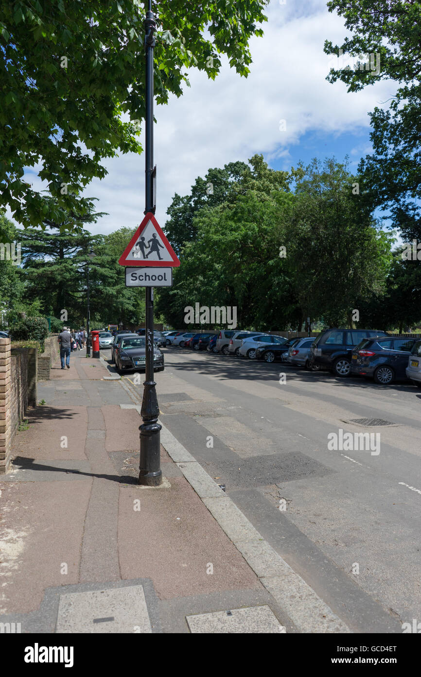 Outdoor street scene showing a School warning sign on a lamppost during a sunny day Stock Photo