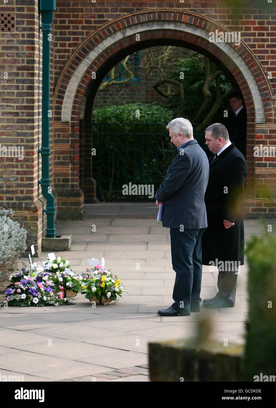 Paul Donnison, father of Harry and Elsie Donnison is comforted as he looks at the flowers laid outside Mortlake Crematorium in Richmond, London, following their cremation service after their bodies were discovered by police officers in a car near the family home in Sussex in January of this year. Stock Photo