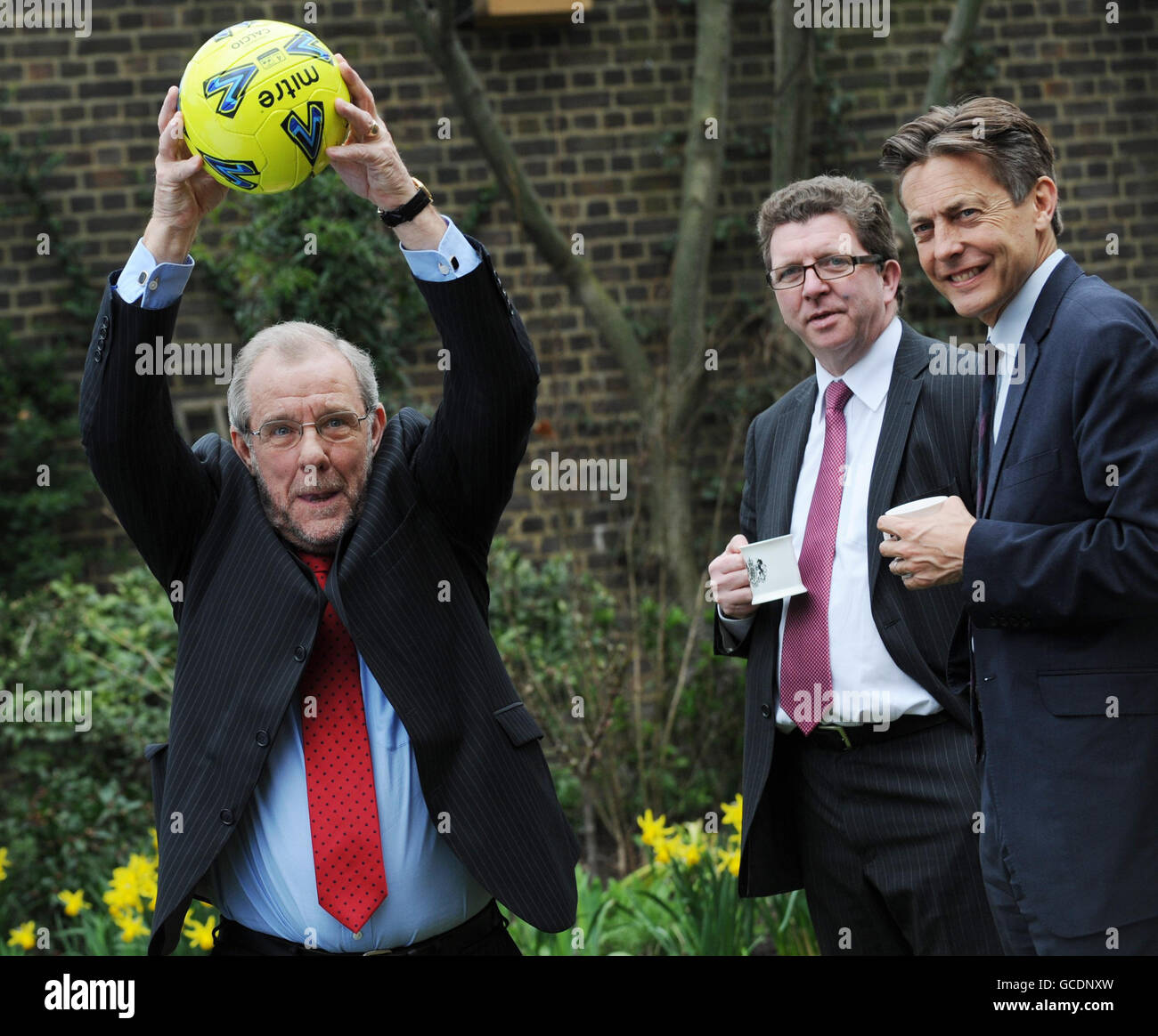 RE-TRANSMISSION AMENDING THE SPELLING OF GERRY SUTCLIFFE. 2018 World Cup bid Ambassador Richard Caborn MP throws a football in the garden of 10 Downing Street, London, with Sports Minster Gerry Sutcliffe (centre) and Culture Minister Ben Bradshaw, where they and Prime Minister Gordon Brown signed a giant England shirt to show their support for the England world cup team this year. Stock Photo