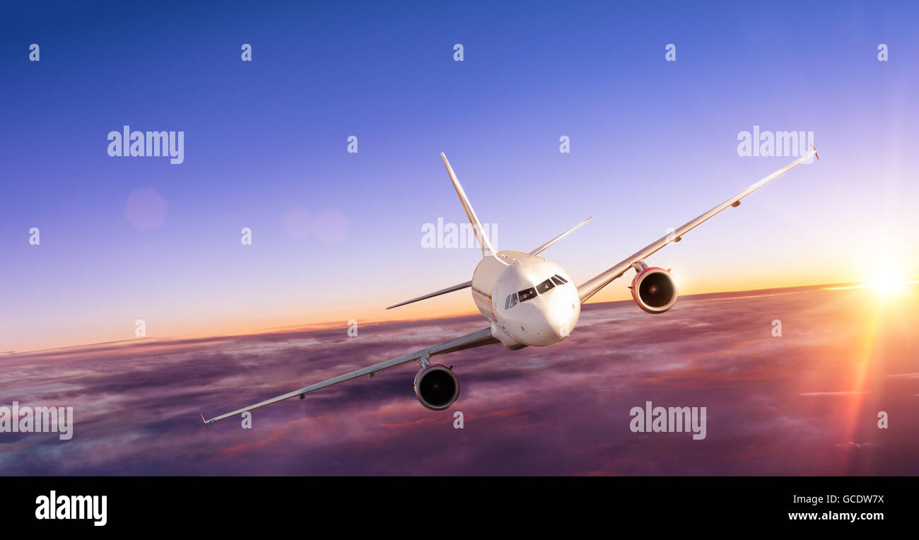 Commercial airplane flying above clouds in dramatic sunset light Stock ...
