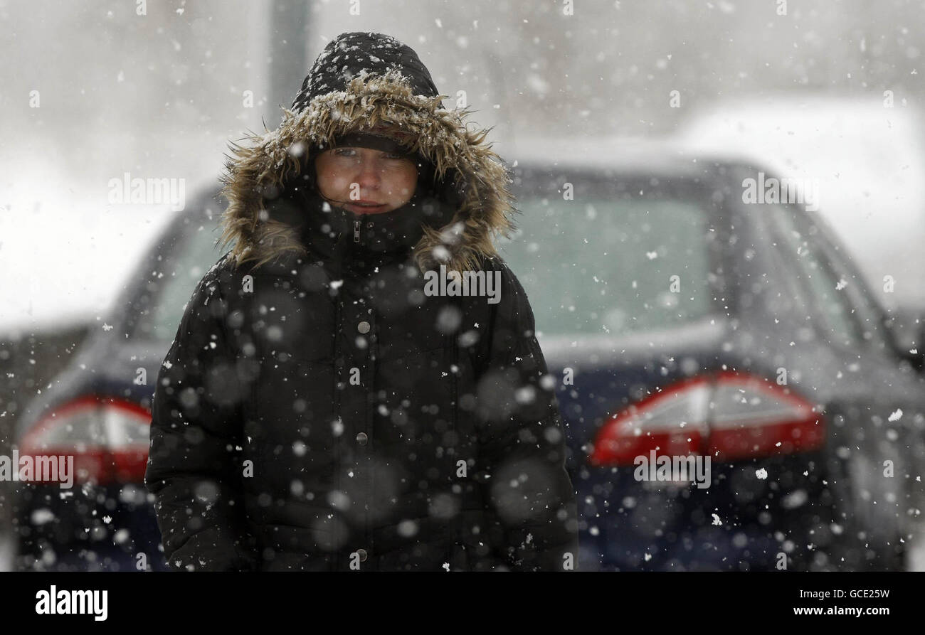 A woman walks through heavy snow in Cavan town, Ireland, as the snow and rain made driving conditions treacherous and further sleet and snow is expected. Stock Photo