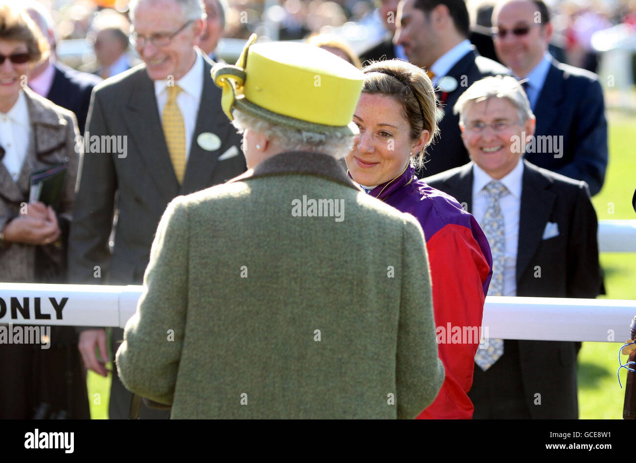 Queen Elizabeth II receives her winners trophy after her horse Tactician ridden by Hayley Turner (right) wons the racinguk.com Maiden Stakes at Newbury Racecourse in Berkshire. Stock Photo