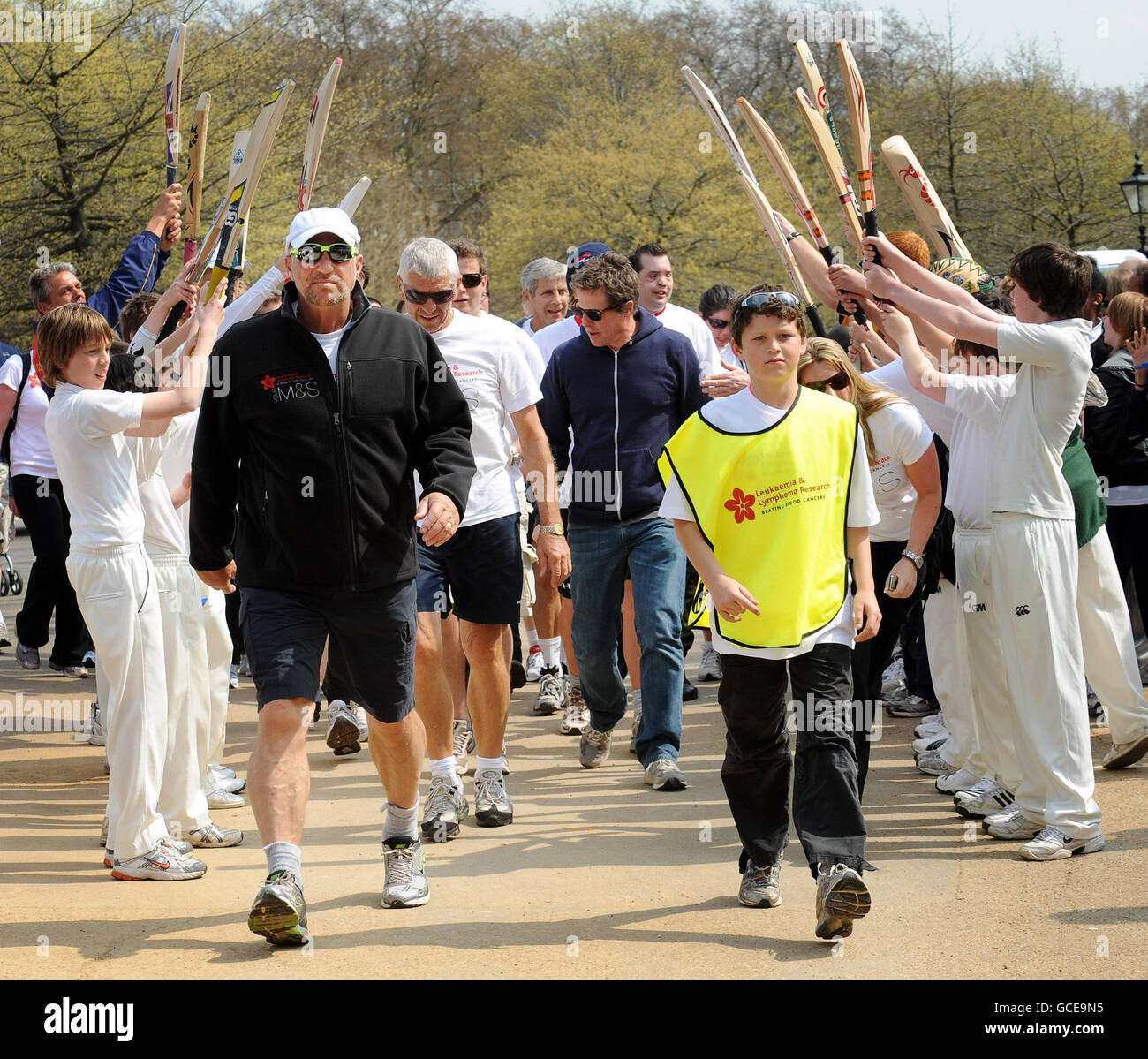 Sir Ian Botham in Hyde Park, London after completing the final leg of his 10 day nationwide Forget-Me-Not walk in aid of Leukaemia Research, where he was accompanied his grandson James, 12, and actor Hugh Grant, (back centre), beneath an honorary arch by cricketing pupils from Emmanuel School in Battersea. Stock Photo