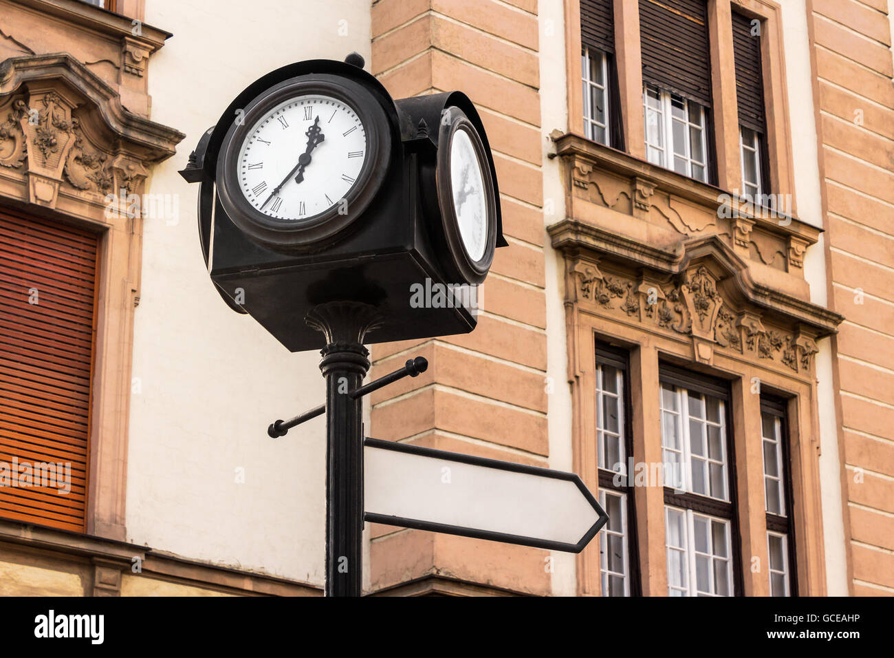 iron city clock on a column with index sign on old european architecture background Stock Photo